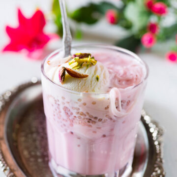 Rose falooda a cooling summer dessert which is rich and delicious. It’s made with milk rose syrup chia seeds and falooda vermicelli and topped with a variety of toppings