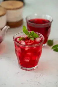 Hibiscus tea recipe. Two glasses of ruby red tea with mint leaves.