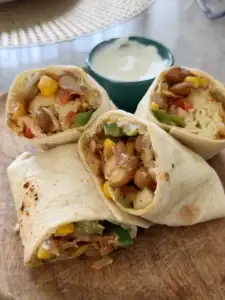 Easy vegetarian bean burrito filled with smoky pinto beans, corn, green bell pepper, fresh vegetables, jalapeños, and cheese