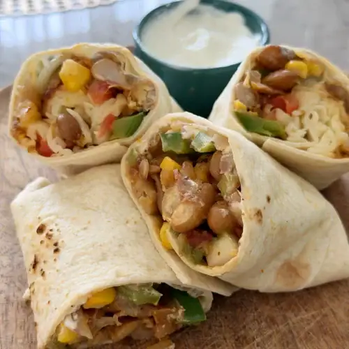 Easy vegetarian bean burrito filled with smoky pinto beans, corn, green bell pepper, fresh vegetables, jalapeƱos, and cheese